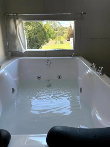 a white bath tub with a window in a bathroom at Pousada Lago do Amanhecer in Capão Alto