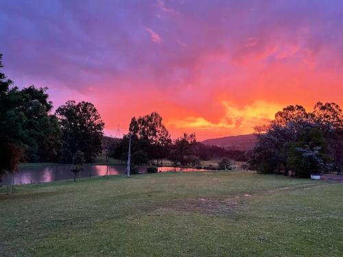 een zonsondergang in een park met een veld en bomen bij Pousada Lago do Amanhecer in Capão Alto