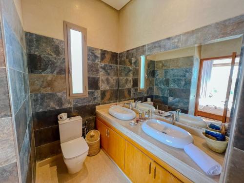 a bathroom with two sinks and a toilet and a mirror at Riad villa saphir & SPA in Marrakech