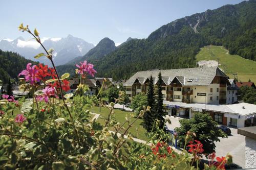 a resort in the mountains with flowers in the foreground at Vitranc Apartments in Kranjska Gora