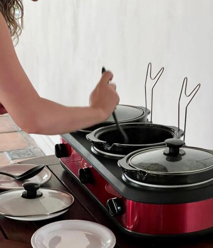 a woman is cooking on a stove with four pans at Hotel Casa Paradiso Guarujá in Guarujá