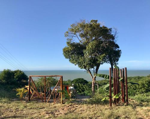 a playground in a field with a tree and the ocean at Kamajorú Ecohabitat in Tubará