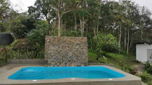 a swimming pool in a yard with a stone wall at Acogedora suite en Liguiqui - Manta 