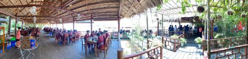 a group of people sitting at tables in a building at Bungalow - Homestay LÀNG BÈ in Ben Tre