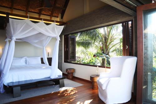 a bedroom with a canopy bed and a chair at Villa Malolo Levu in Malolo