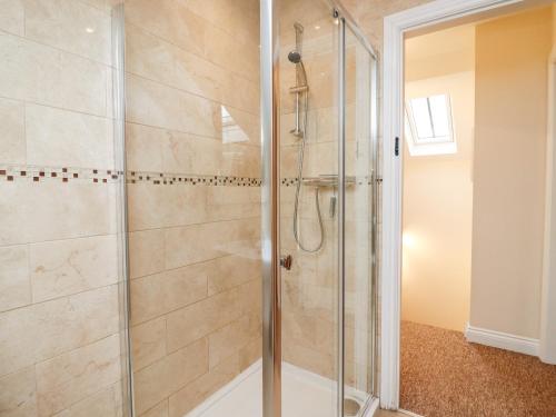 a shower with a glass door in a bathroom at Cow Byre in Little Tew