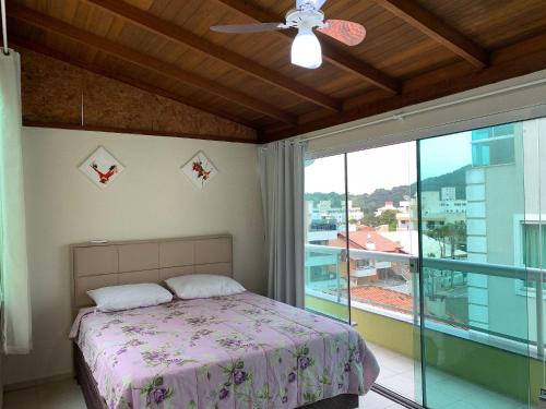 1 dormitorio con cama y ventana grande en Ilha de Molokini Centro Bombinhas -SC, en Bombinhas