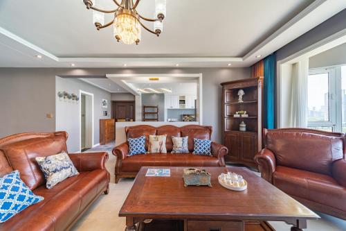 a living room with leather furniture and a table at Cloud & Sea Boutique Apartment in Rizhao