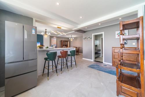 a kitchen with a refrigerator and bar with stools at Cloud & Sea Boutique Apartment in Rizhao