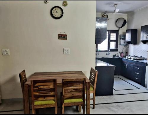 uma cozinha com mesa e cadeiras e um relógio na parede em Angad home fully furnished Ac wifi included ground floor em Kharar