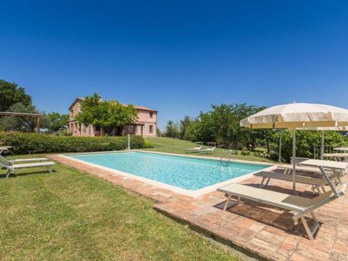 a swimming pool with two chairs and an umbrella at Belvilla by OYO Villa Fufi in Arcevia