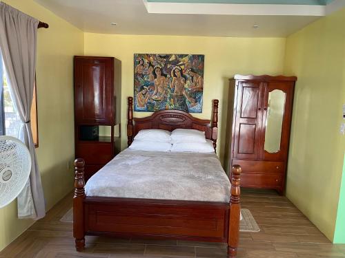 a bedroom with a bed with a painting on the wall at Hidden Treasure Vacation Home Blue Bay Cottage in Caye Caulker