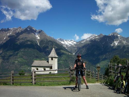 a man on a bike in front of a church at Hotel Weiss in Rablà