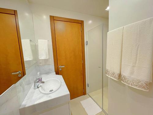 y baño blanco con lavabo y ducha. en Apartamento ha 3 minutos da Rua Coberta - Gramado, en Gramado