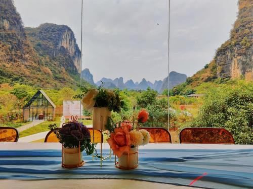 two vases with flowers on a table with mountains in the background at Lanshan Moon Resort in Yangshuo