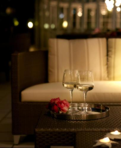 two glasses of wine and a plate with roses on a table at Hotel Feldberg in Riccione