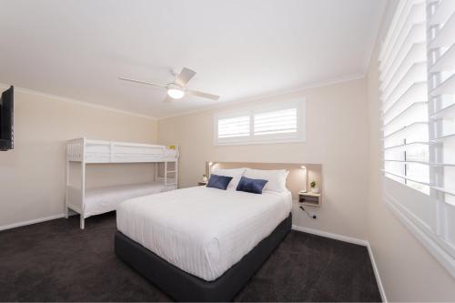 a bedroom with a white bed and a ceiling fan at BIG4 River Myall Holiday Resort in Bulahdelah