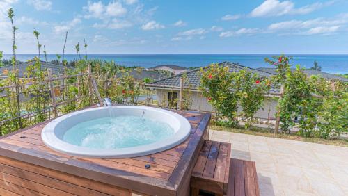a hot tub on a deck with the ocean in the background at Miyakojima Kurima Resort Seawood Hotel in Miyako Island