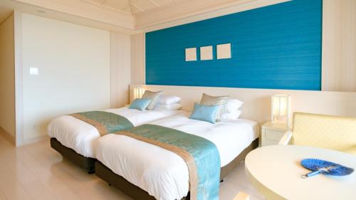 two beds in a room with a blue wall at Miyakojima Kurima Resort Seawood Hotel in Miyako Island
