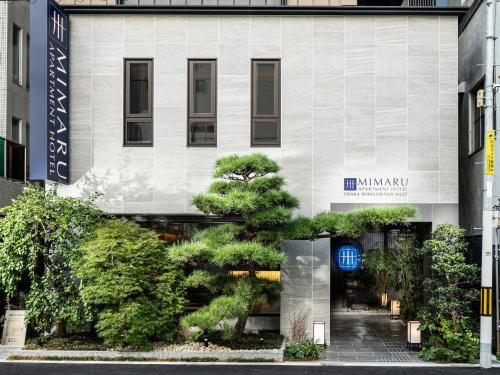 un edificio con árboles delante de él en MIMARU OSAKA SHINSAIBASHI WEST en Osaka