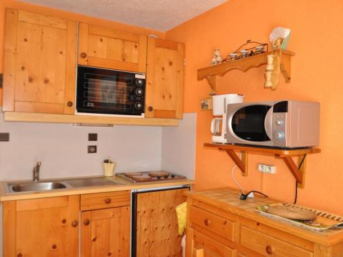 une petite cuisine avec un micro-ondes et un évier dans l'établissement Charmant appart à 600m du centre, balcon S/O, parking, animaux acceptés ! - FR-1-693-27, à Châtel