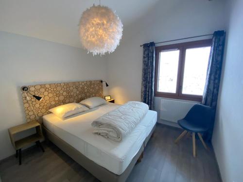 - une chambre avec un lit, une chaise bleue et un lustre dans l'établissement Appartement 2è étage proche centre, 3€/jour Multi Pass, 2 ch., balcon sud, garage privé, Châtel - FR-1-693-33, à Châtel