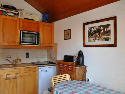 une petite cuisine avec une table et un micro-ondes dans l'établissement Appartement proche centre Châtel, balcon, parking, Multi Pass 2024 - FR-1-693-38, à Châtel