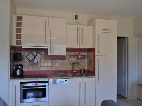 une cuisine avec des armoires blanches et un évier dans l'établissement Appartement vaste et lumineux au centre-ville de Châtel avec Multi Pass été! - FR-1-693-31, à Châtel