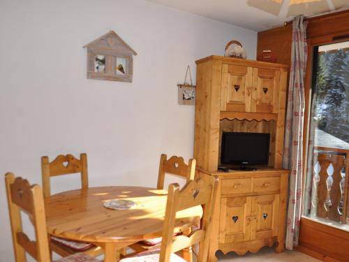 une salle à manger avec une table en bois et une télévision dans l'établissement Appartement cosy à 200m des pistes du Linga, balcon sud, parking inclus ! - FR-1-693-47, à Châtel