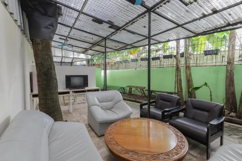 ein Wohnzimmer mit Stühlen, einem Tisch und einem TV in der Unterkunft RedDoorz near RS Sari Asih Ciledug in Jakarta