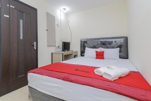 - une chambre avec un grand lit et des serviettes rouges et blanches dans l'établissement RedDoorz near RS Sari Asih Ciledug, à Jakarta