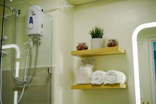 ein Badezimmer mit Holzregalen, Handtüchern und einer Dusche in der Unterkunft Vicar Home by Serin East Tagaytay in Tagaytay