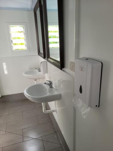 a white bathroom with two sinks and a window at Travellers Paradise in Cairns
