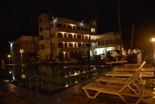 a pool with chairs and a building at night at New Ocean Hill Hotel in Hikkaduwa
