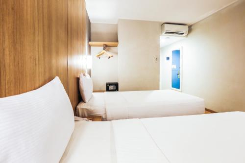 two beds in a hotel room with white sheets at Hotel Citradream Tugu Yogyakarta in Yogyakarta