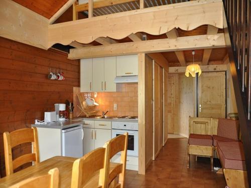 une cuisine avec des armoires blanches et une table et des chaises dans l'établissement Charmant appartement familial avec mezzanine et balcon en centre-ville - FR-1-692-4, à La Chapelle-dʼAbondance