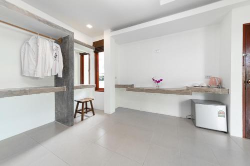 a room with white walls and white tile floors and a white refrigerator at Ibiza Bungalows in Haad Yao