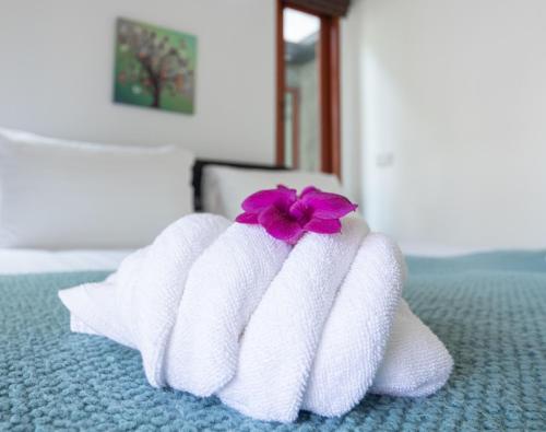 a pair of towels with a flower on a bed at Ibiza Bungalows in Haad Yao