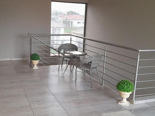 a balcony with three chairs and a table on it at TLZ Prop B&B in Pretoria