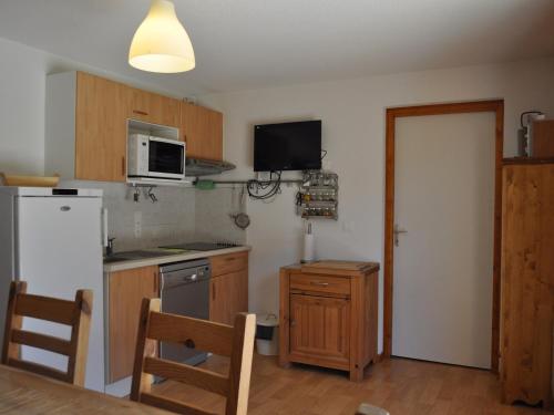 La cuisine est équipée d'un réfrigérateur blanc et d'un four micro-ondes. dans l'établissement Charmant appartement avec grande terrasse exposée plein sud et garage! - FR-1-692-26, à La Chapelle-dʼAbondance