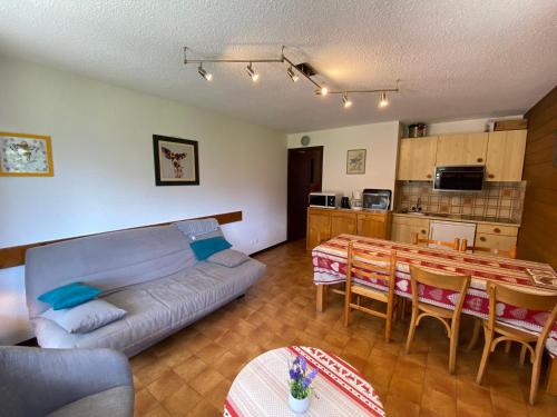 un salon avec un canapé et une table et une cuisine dans l'établissement Appartement cosy au cœur du village avec Multi Pass et balcon sud - FR-1-692-23, à La Chapelle-dʼAbondance