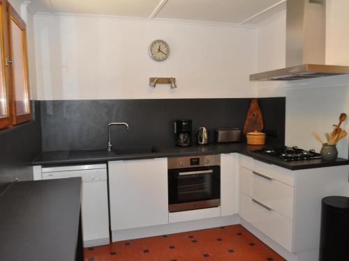 une cuisine avec des placards blancs et une horloge murale dans l'établissement Chalet calme avec cheminée, 4 chambres, idéal famille - FR-1-692-21, à Abondance