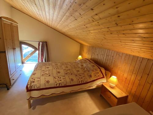 ein Schlafzimmer mit einem Bett mit Holzdecke in der Unterkunft Appartement 2 chambres avec balcon exposé Sud, parking et navettes à proximité - FR-1-692-39 in La Chapelle-dʼAbondance