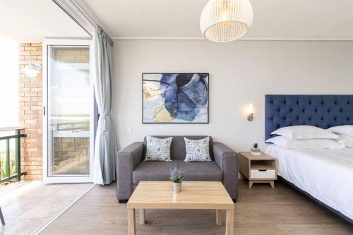 a bedroom with a bed and a couch and a table at Luxury Studio with a View in Summerstrand