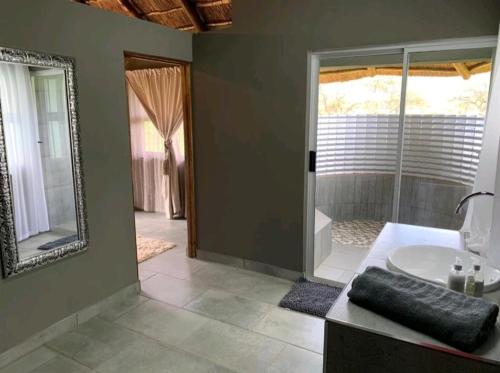 ein Badezimmer mit einer Badewanne, einem Waschbecken und einem Spiegel in der Unterkunft Bradbury Game Lodge and Function Venue in Polokwane