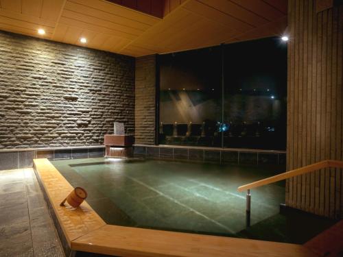 a jacuzzi tub in a room with a brick wall at Kotohira Kadan in Kotohira