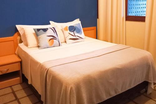 um quarto com uma cama com lençóis brancos e almofadas em Pousada Casa Grande em Bonito