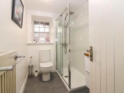 a bathroom with a toilet and a glass shower at Shortbread Cottage in Cupar