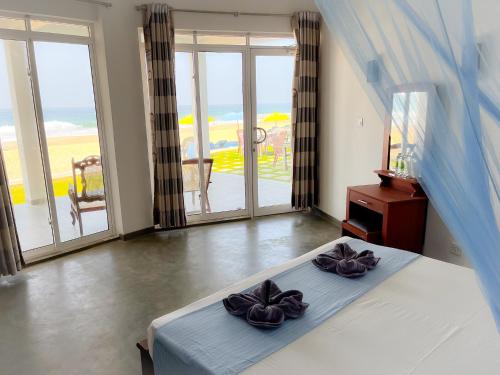 1 dormitorio con cama y vistas al océano en Pearl Island Beach Hotel en Hikkaduwa