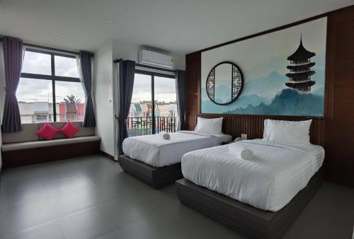 a bedroom with two beds and a large window at โรงแรมชลาลัย กระบี่ Chalalai Hotel Krabi in Ban Nua Khlong